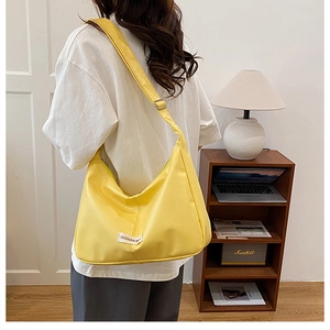 Detail of yellow crescent hobo bag with adjustable strap and fashion tag in modern room