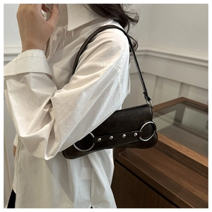 Détail du sac baguette en cuir mat avec anneau argenté et rivets décoratifs
