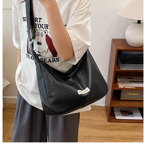 Detail of soft black leather hobo bag with fashion logo tag in a cozy lifestyle setting