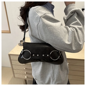 Gros plan d'un sac à bandoulière noir rétro avec anneau argenté et rivets punk portés