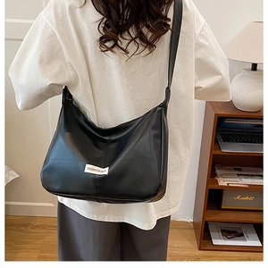 Detail of black faux leather tote bag with FASHION BAG label and middle seam design