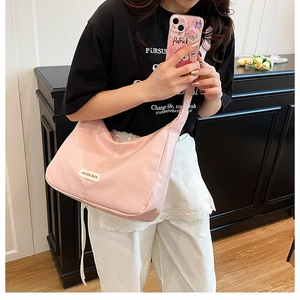 Detailed view of pink nylon shoulder bag featuring a white fashion label on the front