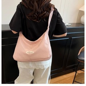 Rear view of pink nylon crescent crossbody bag with white fashion tag on adjustable strap