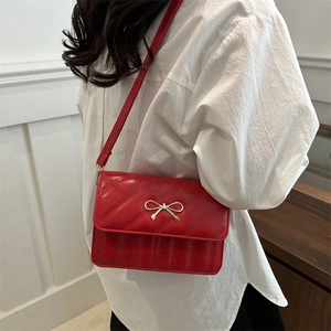 Fashionable red quilted shoulder bag with golden bow buckle and minimalist design