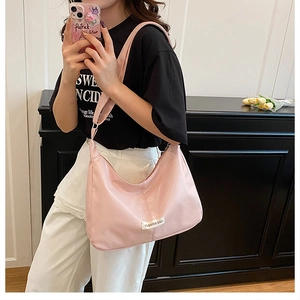Detail of pink fashion tote bag with white woven label on nylon crescent shoulder bag