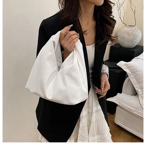Detail of white pleated cloud bag showing soft leather texture and elegant hand-held design