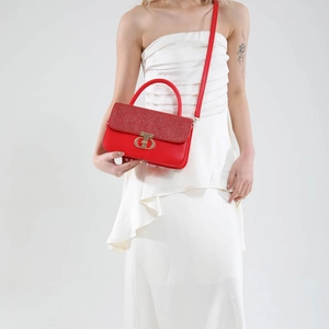 Red rhinestone flap handbag with gold CD logo and top handle on a white background