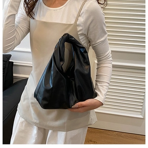 Detail of black cloud bag featuring a unique knotted handle and soft pleated faux leather