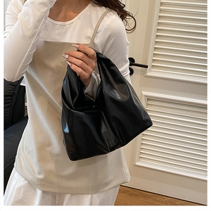 Detail of a minimalist black pleated leather bucket bag shown on a model for daily styling