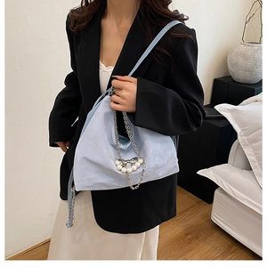 Hellblaue Wildledertasche mit Perlen, Silberketten und Schleifen-Detail an einem Modell