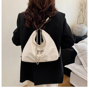 Detailansicht der weißen Ledertasche mit silberner Schmetterlingskette und Perlenanhänger
