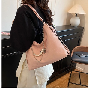 Detail der rosa Schultertasche mit eleganter Schmetterlingskette und Perlenanhänger