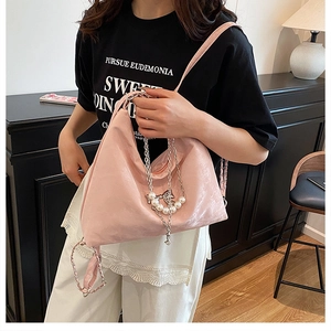 Nahaufnahme der rosa glänzenden Hobo-Tasche mit Schmetterlingskette und Perlen