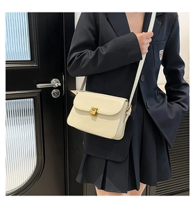 Detail of cream leather crossbody bag featuring a classic gold rectangular push-lock closure