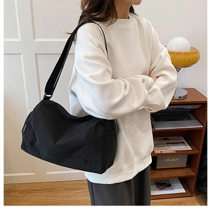 Détail du sac bandoulière en nylon noir avec sangle réglable et étiquette mode latérale
