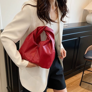 Minimalist red leather knot handbag with pleated design shown on a professional model