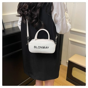 Detail of white woven cylindrical handbag with black logo and top handles shown on model