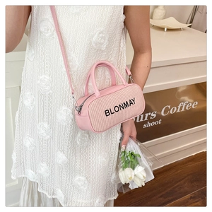 Pink cylinder handbag with textured weaving and leather stitching shown with white lace dress