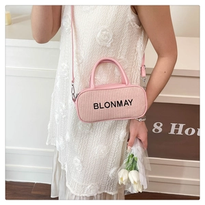 Detail of pink woven handbag featuring leather handles and adjustable shoulder strap