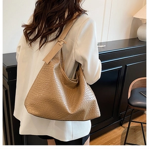 Detail of a large khaki woven tote bag showing Intrecciato texture and fashion tag