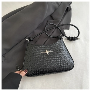 Close-up of black crocodile embossed leather shoulder bag with silver star ornament