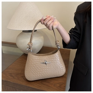 Detail view of khaki woven leather shoulder bag featuring a silver star logo and knotted handle