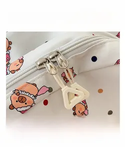 Detail view of smooth double zippers and pink cartoon pig print on the white backpack