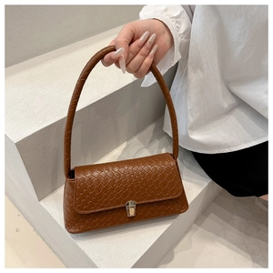 Detail of brown woven faux leather shoulder bag featuring a gold square buckle lock