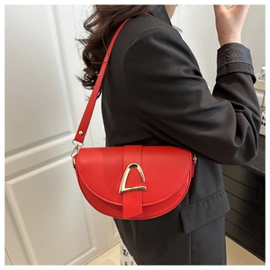 Detail of red leather saddle bag with gold triangle buckle worn on shoulder