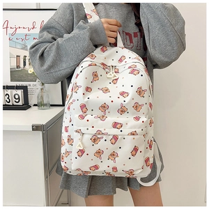 Detail of white backpack featuring cute pink cartoon pig prints and a front zipper pocket