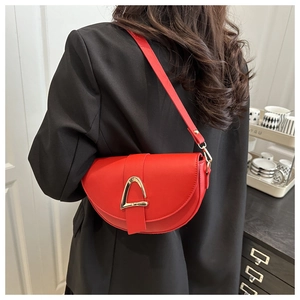 Detail of red saddle bag with gold triangle buckle shown on model wearing black blazer