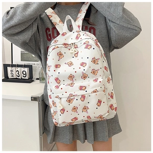 Detailed view of white backpack with cartoon bear prints and polka dots on a person
