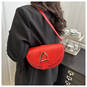 Detail view of a bright red semi-circular saddle bag worn as an underarm shoulder bag