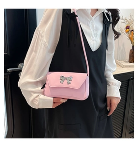 Close-up of pink crossbody bag with a silver metal bow accent worn by a model