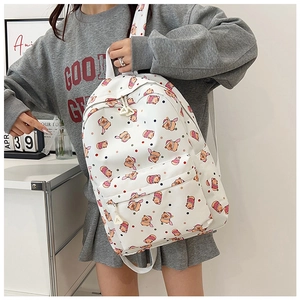 Lifestyle shot of white school backpack featuring cute cartoon bear print and front pocket