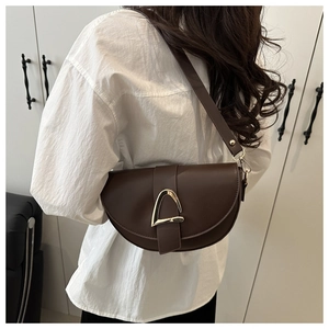 Deep brown saddle bag with gold horsebit detail styled on model in white shirt