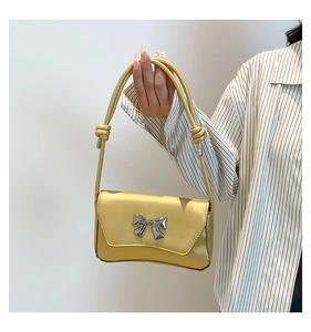 Detail of a chic yellow bow shoulder bag with glossy leather and silver metal accent