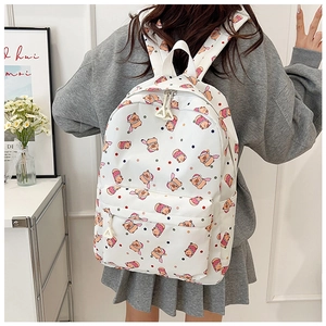 Detail view of the white backpack featuring cute cartoon pig prints and dual zipper pockets