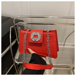 Gros plan d'un sac à main rouge en similicuir avec une grande boucle carrée en strass