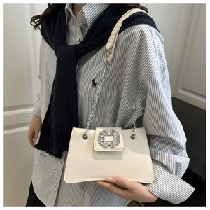 Détail du sac bandoulière blanc cassé avec boucle en cristal et chaîne argentée