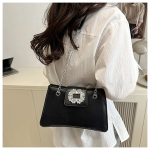 Detail of elegant black faux leather shoulder bag with large crystal buckle and silver chain
