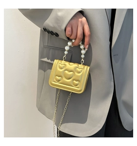 Detail of gold heart-quilted mini bag with pearl handle and metal chain strap