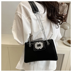 Detail of black faux leather shoulder bag featuring a sparkling rhinestone buckle and chain strap