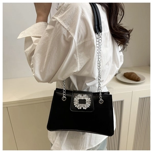 Detail of elegant black shoulder bag with a crystal-embellished buckle on satin finish