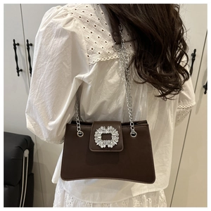 Detail of a brown leather shoulder bag with a crystal buckle and chain strap