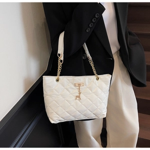 Close-up of white quilted tote bag featuring golden deer charm and chain shoulder strap
