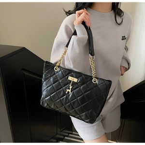 Close-up of quilted black tote bag with gold chain strap and metal deer charm detail