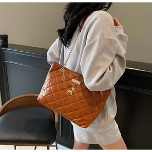 Detail of quilted texture on brown tote bag with gold chain and deer charm