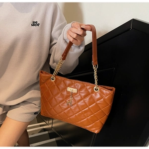Close-up of brown quilted faux leather tote bag with golden deer pendant and chain strap