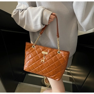Close-up of brown quilted tote bag with gold chain strap and deer pendant on stairs